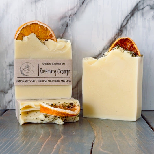 Three bars of Rosemary Orange soap with dried orange slices on a marble background